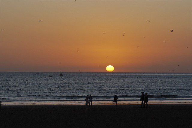 Sunset over Agadir beach, with orange hues lighting up the horizon and gentle waves of the Atlantic Ocean